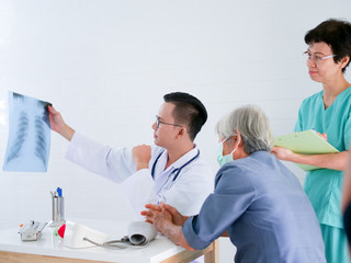 Obraz premium Doctor holding x-ray film in hands present to elderly woman in hospital .Health care concept.