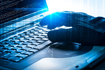 The abstract image of the hacker's hand using a laptop in the empty white room overlay with source...