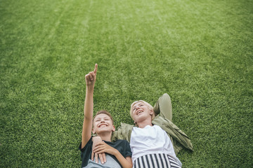high angle view of happy mother and son looking up while lying together on green lawn