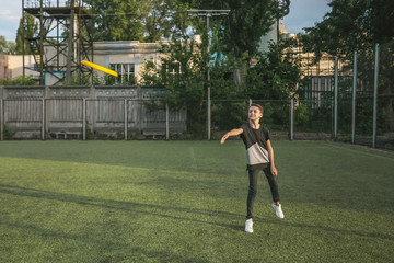 full length view of boy throwing flying disc on green lawn