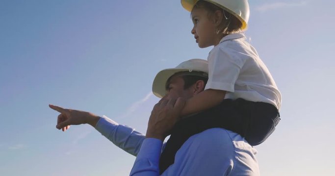 A father engineer shows his project to his daughter for the construction of a wind farm. The daughter is interested in renewable energy. Concept of: family, engineering, future love for nature.