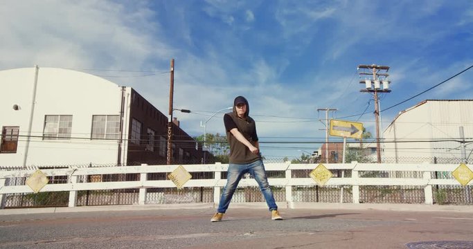 Man hip hop dancing outside in street on sunny day 