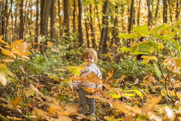 happy little child, baby girl laughing and playing in autumn park