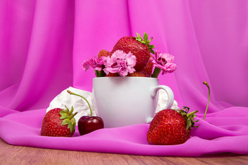 Obraz na płótnie Canvas cup with strawberries, flowers, cherries on a pink background