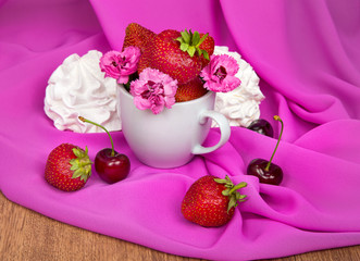cup with strawberries, flowers, cherries on a pink background