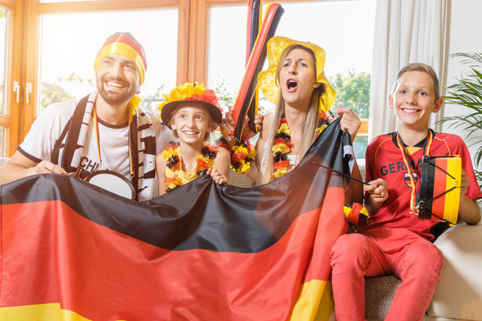Happy family cheering for the German soccer team in front of TV