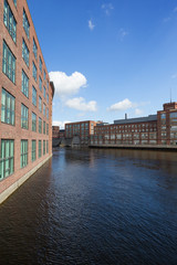 Fototapeta premium Old red brick industrial buildings along the Tammerkoski rapids in downtown Tampere, Finland on a sunny day.
