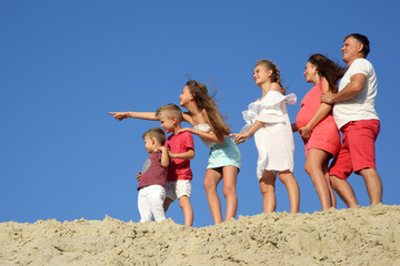 family with children standing together on a sandy hill
