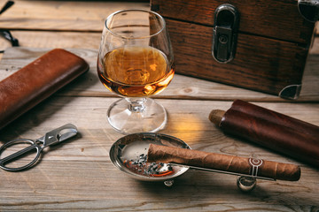 Cuban cigar and a glass of cognac brandy on wooden background - obrazy, fototapety, plakaty