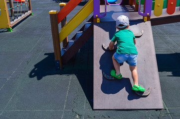 the little boy climbs up the wall. the child climbs up. the children's playground is equipped with modern exercise equipment. a child easily overcomes an obstacle
