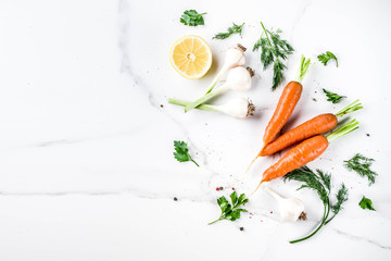 Cooking background with Fresh Vegetables for healthy dinner; carrots, herbs, olive oil, garlic; white marble background flat lay