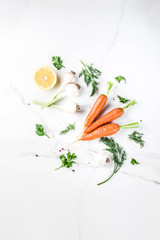 Cooking background with Fresh Vegetables for healthy dinner; carrots, herbs, olive oil, garlic; white marble background flat lay