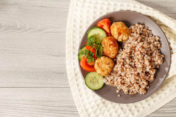 Plate with buckwheat, fried meat cutlets, pieces of fresh cucumbers and tomatoes
