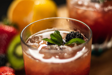 Bonito cóctel con zarzamoras, fresas y hojas de menta en un bonito vaso de vidrio sobre un fondo de madera