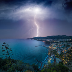 Naklejka na ściany i meble Huge lightning from dark stormy sky strikes coastal city