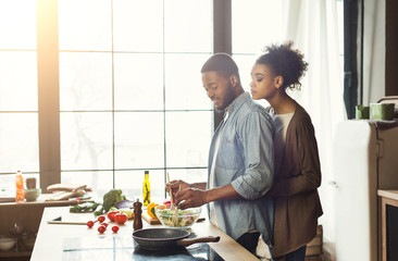 Loving african-american couple cooking in loft kitchen
