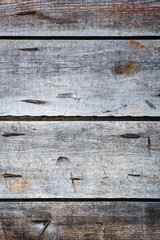 Vintage background from old gray weathered boards with nails with remnants of red paint