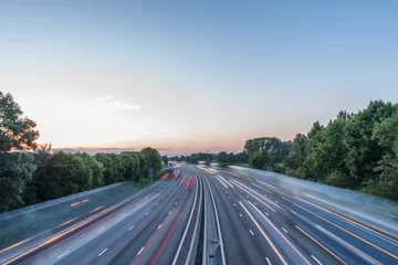 Foto op Plexiglas Uitzicht op de zonsondergang zwaar verkeer dat zich met hoge snelheid voortbeweegt op de Britse snelweg in Engeland © Jevanto Productions