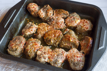 Delicious pieces of baked meat in a black pan