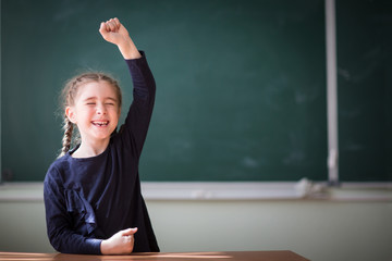 schoolgirl rejoice showing fallen tooth. first grader ready for school. happy child at background of school Board