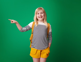 school girl pointing at something against green background