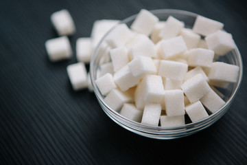 Fototapeta na wymiar White sugar cubes on black table