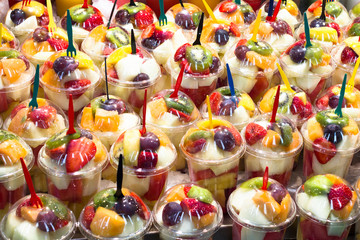 Fresh fruits on the counter. Grapes, strawberries, kiwi, melon, peach in a plastic glass.