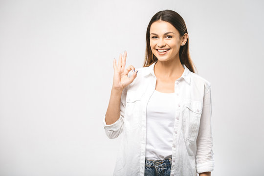 Young happy cheerful woman showing ok sign. Confident young businesswoman giving the thumbs up against a white background. Place for text.