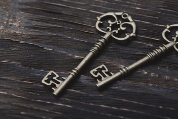 Two vintage bronze keys on a wooden table
