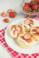 Obraz na płótnie Canvas Homemade cottage cheese pancakes with sour cream and fresh strawberry on white wooden background. Healthy breakfast.