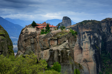 Magnificent autumn landscape. Monastery Holy Trinity, Meteora, Greece. UNESCO world heritage Site. Epic landscape with temple at the edge of cliff at dramatic sky background.