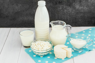 Different types of dairy products on white wooden background. Milk, cottage cheese, cheese, sour cream and kefir.