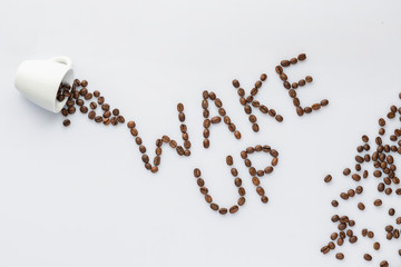 Roasted coffee beans make wake up letters on grey background