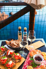 Romantic dinner for two at sunset. White wine and Tasty italian snack: fresh bruschettes  and meat on the board in outdoor cafe with amazing view in Manarola