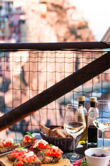 Romantic dinner for two at sunset. White wine and Tasty italian snack: fresh bruschettes  and meat on the board in outdoor cafe with amazing view in Manarola