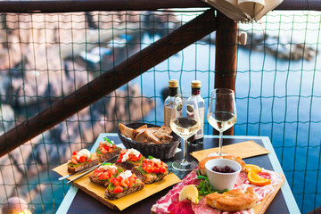 Romantic dinner for two at sunset. White wine and Tasty italian snack: fresh bruschettes  and meat on the board in outdoor cafe with amazing view in Manarola - 209889391