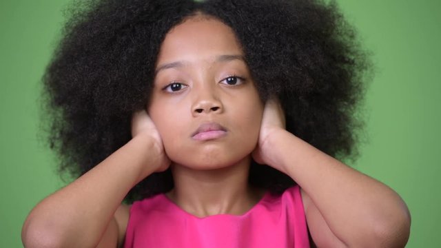Young cute African girl with Afro hair covering ears as three wise monkeys concept