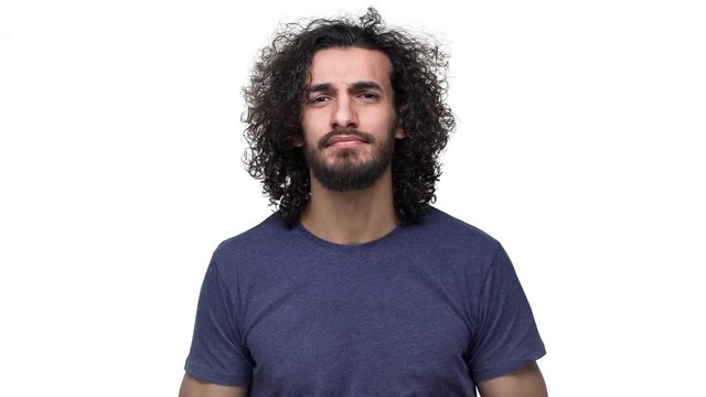 Portrait of emotional guy with curly hair in casual dark blue t-shirt gesturing with hand, over white background in slow motion. Concept of emotions