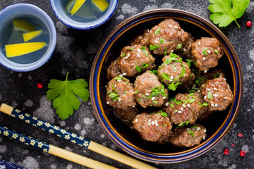 Beef meatballs in bowl with sauce, brown with sesame and parsley, tatsy snack