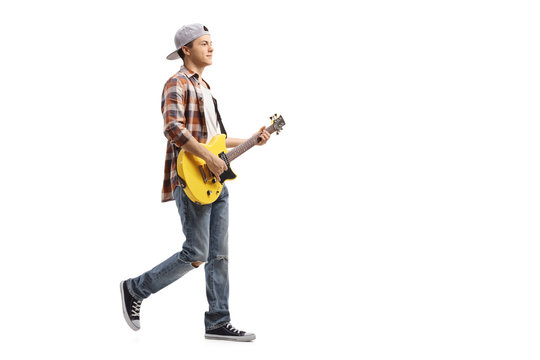 Teenage boy walking and playing an electric guitar