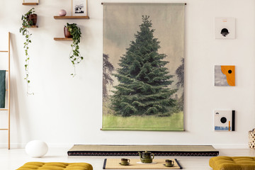 Real photo of a tree graphic hanging on white wall above a tatami mat in simple japanese interior...