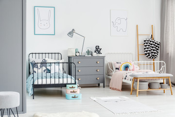 White bed for a girl and black one for a boy in a siblings bedroom interior with posters of a...