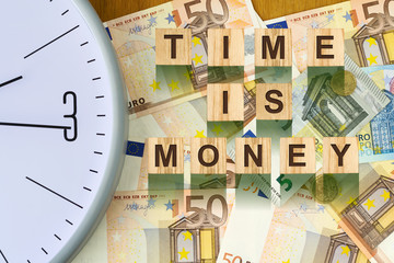 Word, Time Is Money composed of letters on wooden building blocks against the background of Euro banknotes. Concept business, finance.