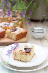 Pieces of fruit pie with pieces of plums and peach and a bouquet of flowers on a wooden table. Rustic style.