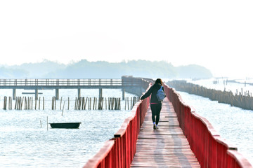 Walking over the wooden red bridge across the sea at Gulf of Thailand.
