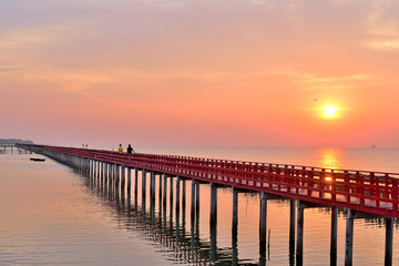Fototapeta na wymiar Sunrise and beautiful sky background at wooden red bridge over the sea.