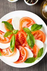Close-up photo of caprese salad with ripe tomatoes, basil, buffalo mozzarella cheese. Italian and Mediterranean food concept. Fresh and healthy organic meal. Starter and antipasti. 