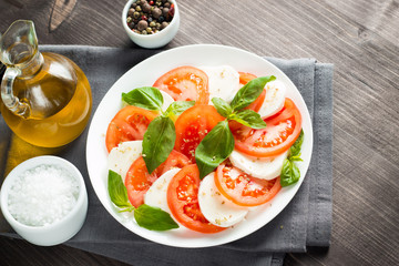Close-up photo of caprese salad with ripe tomatoes, basil, buffalo mozzarella cheese. Italian and Mediterranean food concept. Fresh and healthy organic meal. Starter and antipasti. 