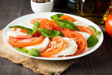 Close-up photo of caprese salad with ripe tomatoes, basil, buffalo mozzarella cheese. Italian and Mediterranean food concept. Fresh and healthy organic meal. Starter and antipasti. 