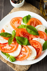 Close-up photo of caprese salad with ripe tomatoes, basil, buffalo mozzarella cheese. Italian and Mediterranean food concept. Fresh and healthy organic meal. Starter and antipasti. 